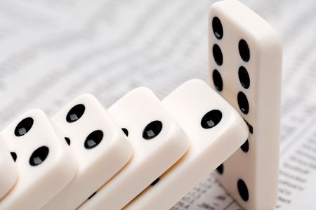 Horizontal image of falling dominoes on a newspaper stock reportの写真素材
