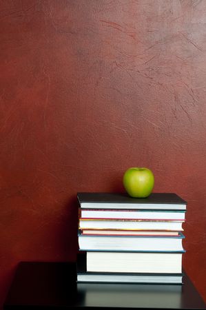 Vertical image of a stack of books with a green appleの写真素材