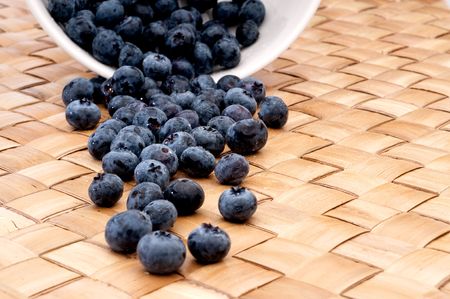vertical image of fresh blueberries spilling from a bowlの写真素材