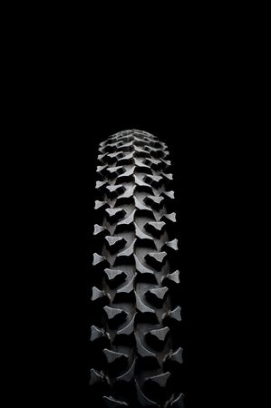 Vertical close up of a mountain bike tire on black