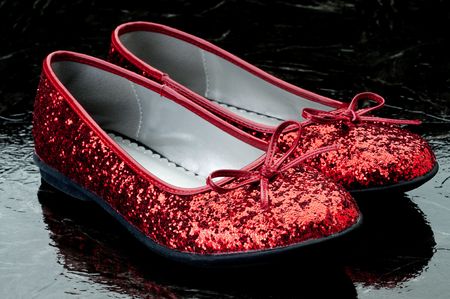 Horizontal image of sequined red slippers on dark tile.の写真素材