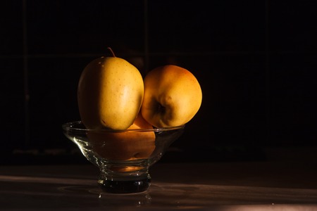 Yellow apples in a vase on a dark background.の写真素材