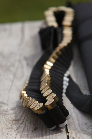 Bullets for the gun lie on a wooden tableの写真素材