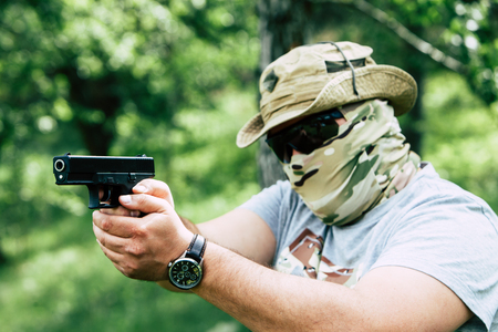 A man shoots a pistol. He looks at us