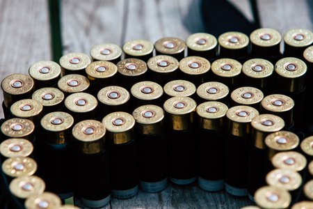 Bullets for the gun lie on a wooden tableの写真素材