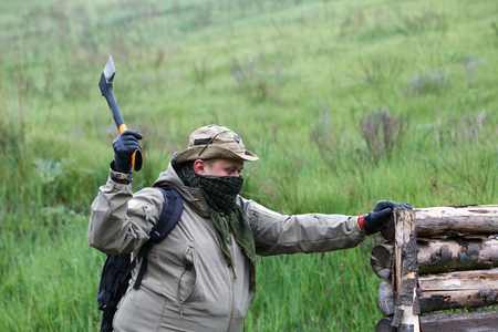 Male traveler with an ax and a backpack on a background of green mountains and firewood.の写真素材