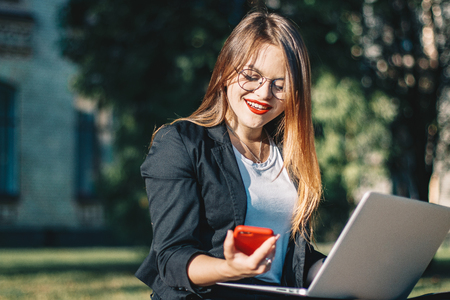 Business woman working in the park and talking on the phoneの写真素材