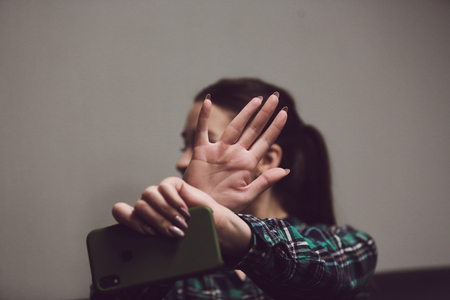The girl refuses to photograph. She is holding a phone in her hands and is closing her hands on the cameraの写真素材