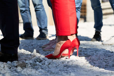 A woman in red trousers and red shoes stands on the rocks at the construction. High quality photoの写真素材
