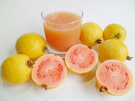 A glass of fresh guava juice and guava fruits from Hawaii on white backgroundの写真素材
