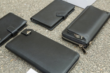 Black wallet purse on pavement. White package with no inscriptions