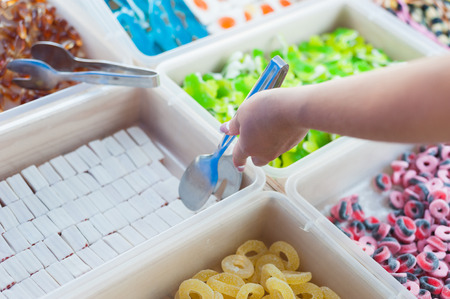 young woman takes jelly candies over the counterの写真素材