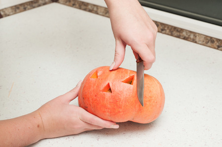 two hands cutting pumpkin on wooden deskの写真素材