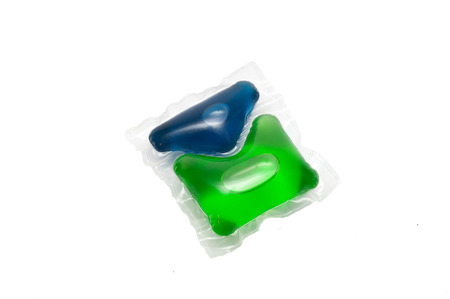 Green and blue gel capsules with laundry detergent on a white backgroundの写真素材
