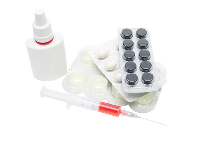 Pills in a blister pack, syringe with red liquid and nasal spray on a white backgroundの写真素材