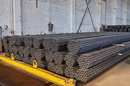 Metal pipes in a warehouse. Stacks of new round steel pipe in factory.の写真素材