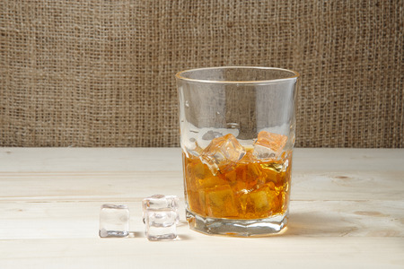 Glass of whiskey with ice on wooden tableの写真素材