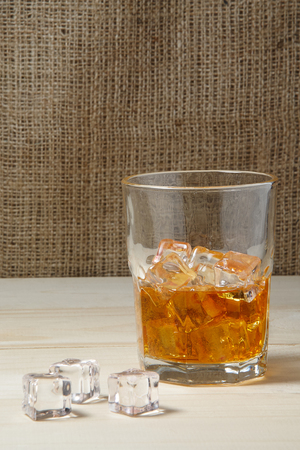 Glass of whiskey with ice on wooden tableの写真素材