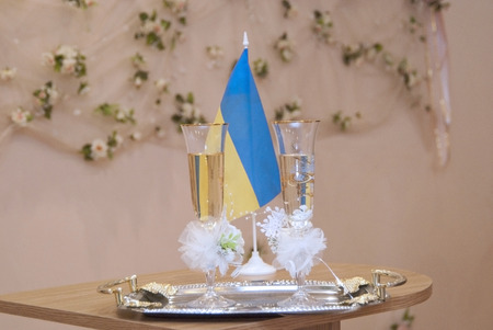 Two wedding glasses with champagne on table and flag of Ukraine.の写真素材