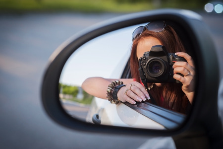 Young redhead woman take selfie on car wing mirrorの写真素材
