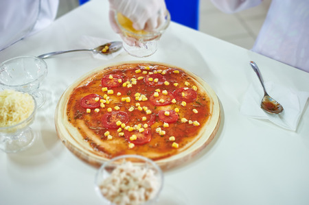 Hand of chef baker in white uniform making pizza at kitchen. Tilt-shift effectの写真素材