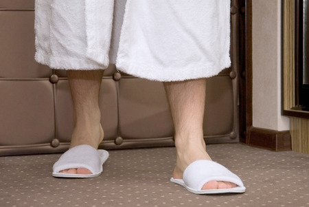Young man legs with white bathrobe and slippers on carpetの写真素材