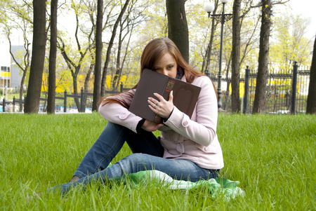 Beautiful redhead woman with book in parkの写真素材