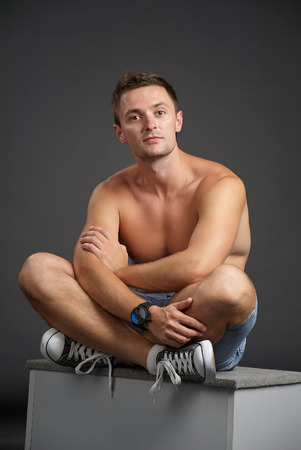 Portrait of a relaxed man sitting on a cube in yoga positionの写真素材