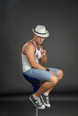 Portrait of man in hat sitting on a bar stool and pointing fingerの写真素材