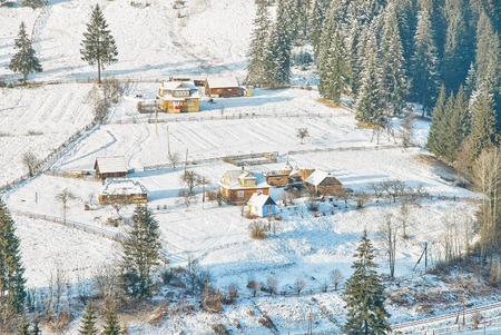 Ukrainian wooden rustic houses covered by snow. Beautiful snow forest behindの写真素材