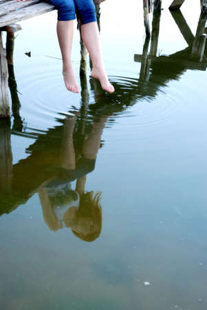 Girl sit on the small bridge with reflection on waterの写真素材
