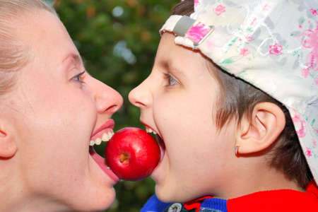 Girls try bite off red appleの写真素材