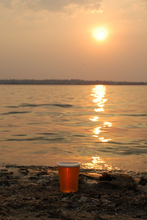 Beer cup in sunset light on river shoreの写真素材
