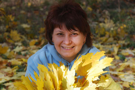 pretty women pick up of leaves in autumn parkの写真素材