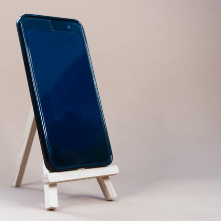 Mobile phone on easel on gray background