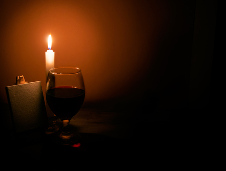 Still-life from a candle a glass of wine and an easelの写真素材