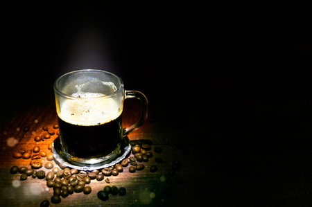 Cup of coffee and scattered grains on a wooden tableの写真素材