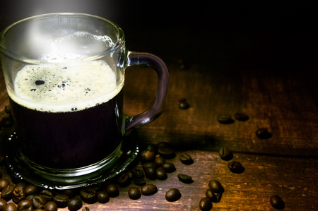 Cup of coffee and scattered grains on a wooden tableの写真素材