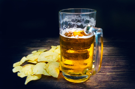 Just a glass of beer and chips on a vintage wooden tableの写真素材