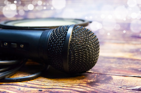 Microphone and speaker on the background of blurry particles and wooden table