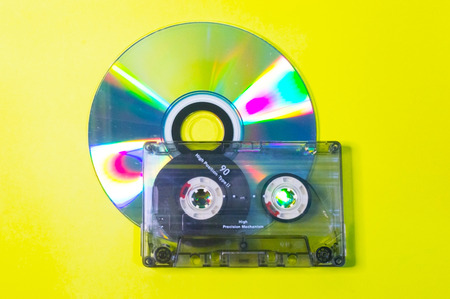 Compact disc and audio cassette on a yellow background.の写真素材