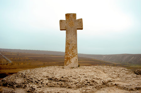 Stone cross on a cliff on a cloudy day near the monastery