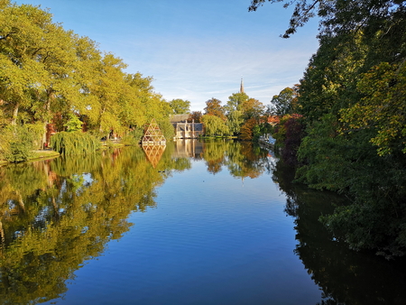Autumn tree colors reflected in a lake in Brugesの写真素材