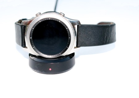 A smart-watch sitting on a charging pad isolated on a white backgroundの写真素材