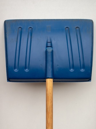 Well-worn blue snow shovel and wooden handle isolated on whiteの写真素材
