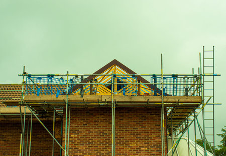 Scaffolding and wooden planks erected around an extension to a house