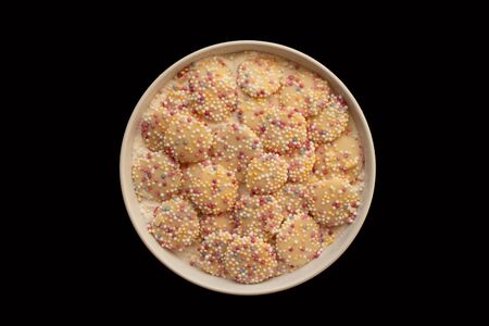 A small dish of white chocolate candy buttons isolated on a black backgroundの写真素材