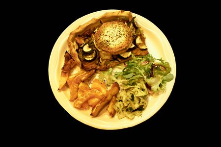 a down view of a plate of flan, chips and salad isolated against a black backgroundの写真素材