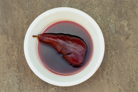 Overview of a dish of poached pear isolated on a stone background