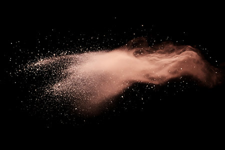 A dynamic abstract image captures a burst of fine colored powder and illuminated particles, forming a wispy, smoky cloud with fiery orange and pink hues.の素材